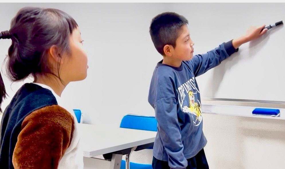 ホワイトボードに英語を書く小学生