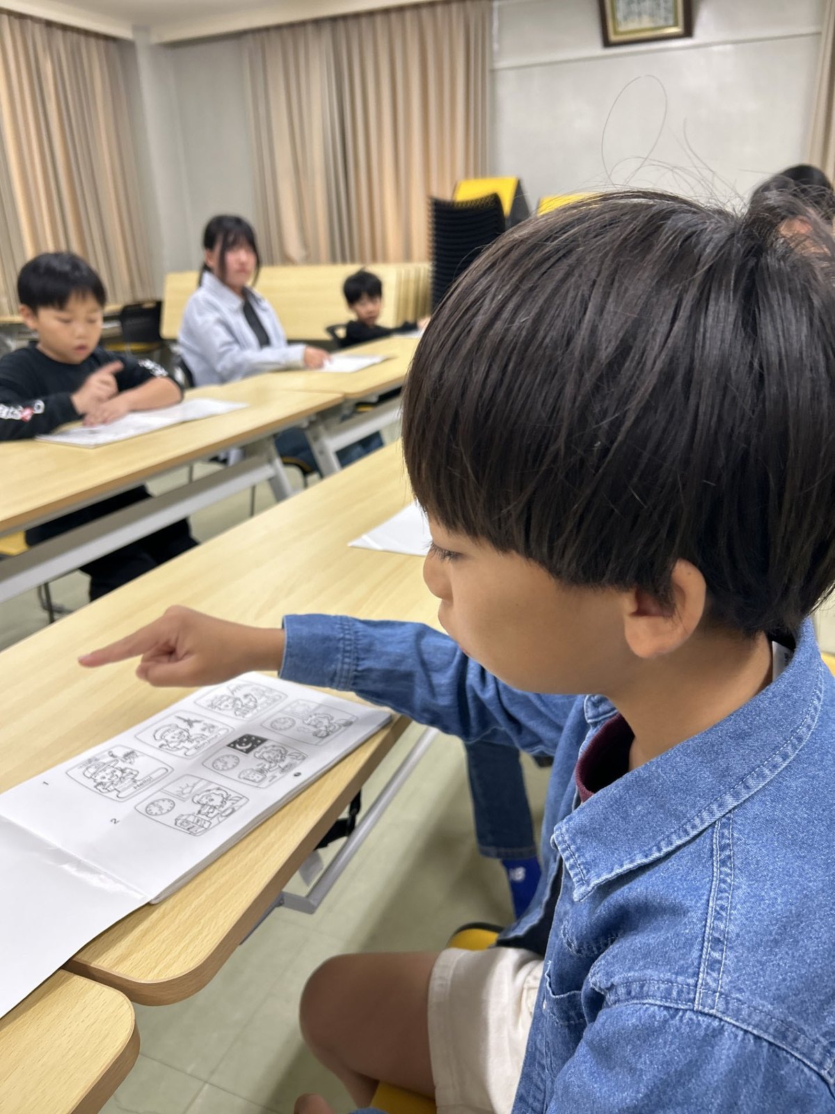 プリントを指さしながら英語を読む男の子