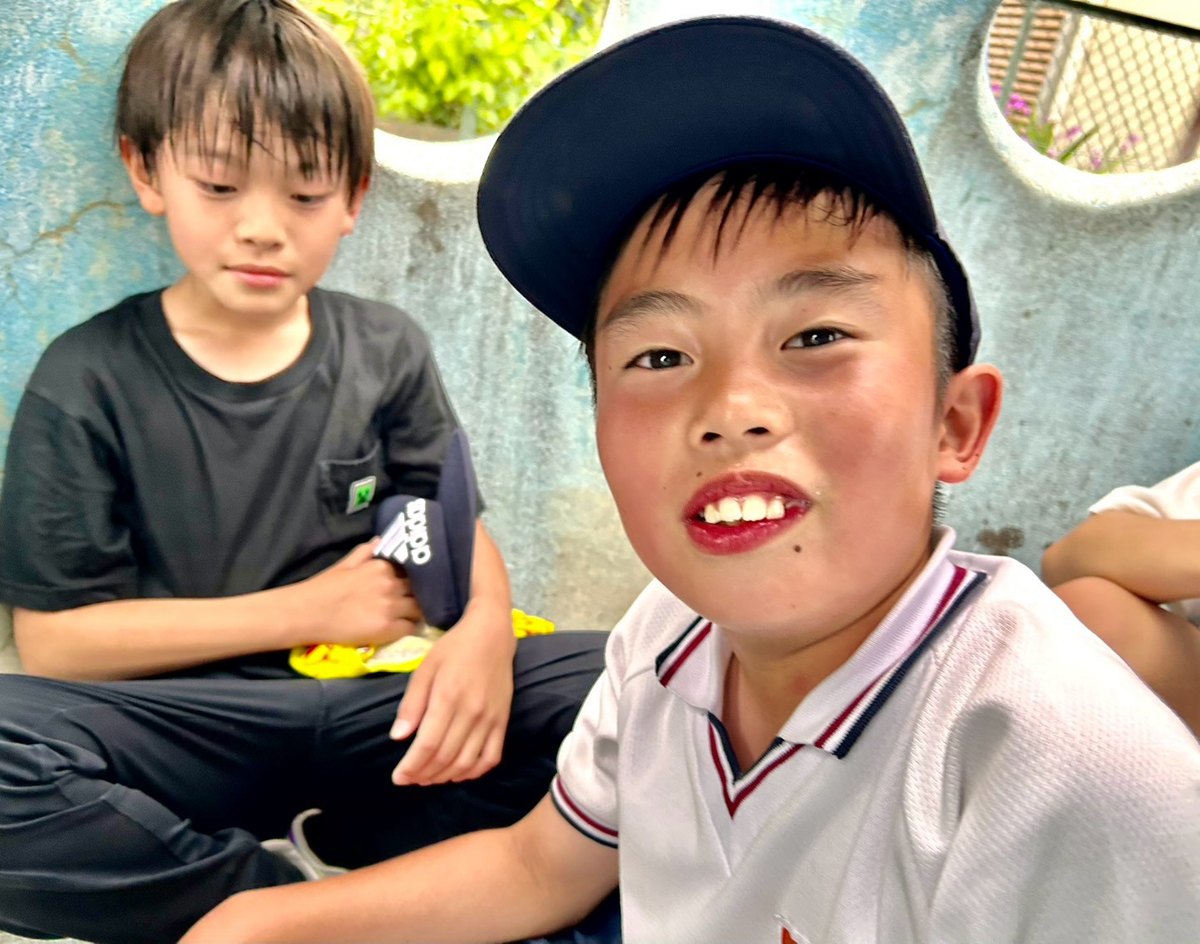 公園レッスンの休けい中、カメラに笑顔を向ける男の子