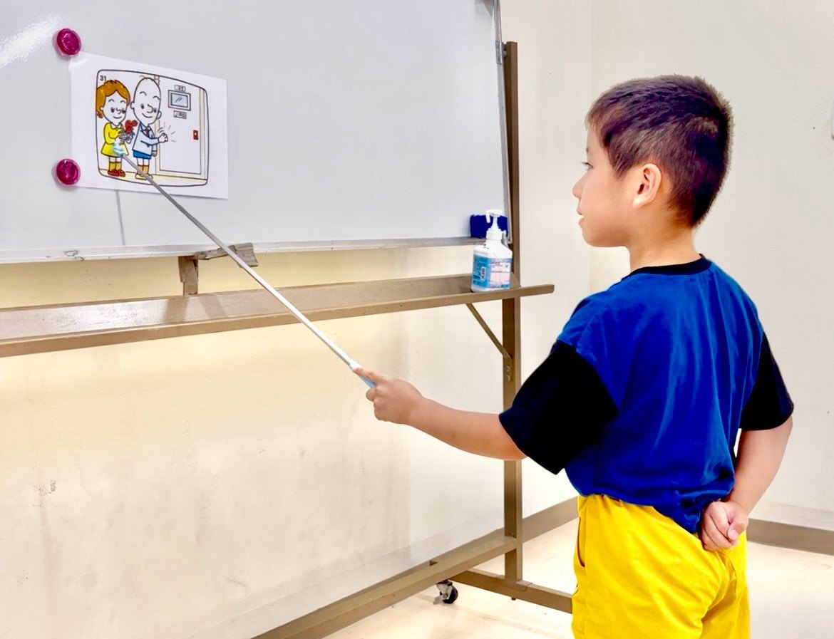 指し棒でホワイトボードの絵を示しながら答える男の子