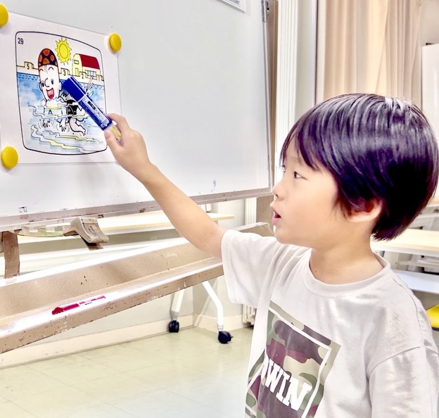 ホワイトボードの絵を指さして答える男の子