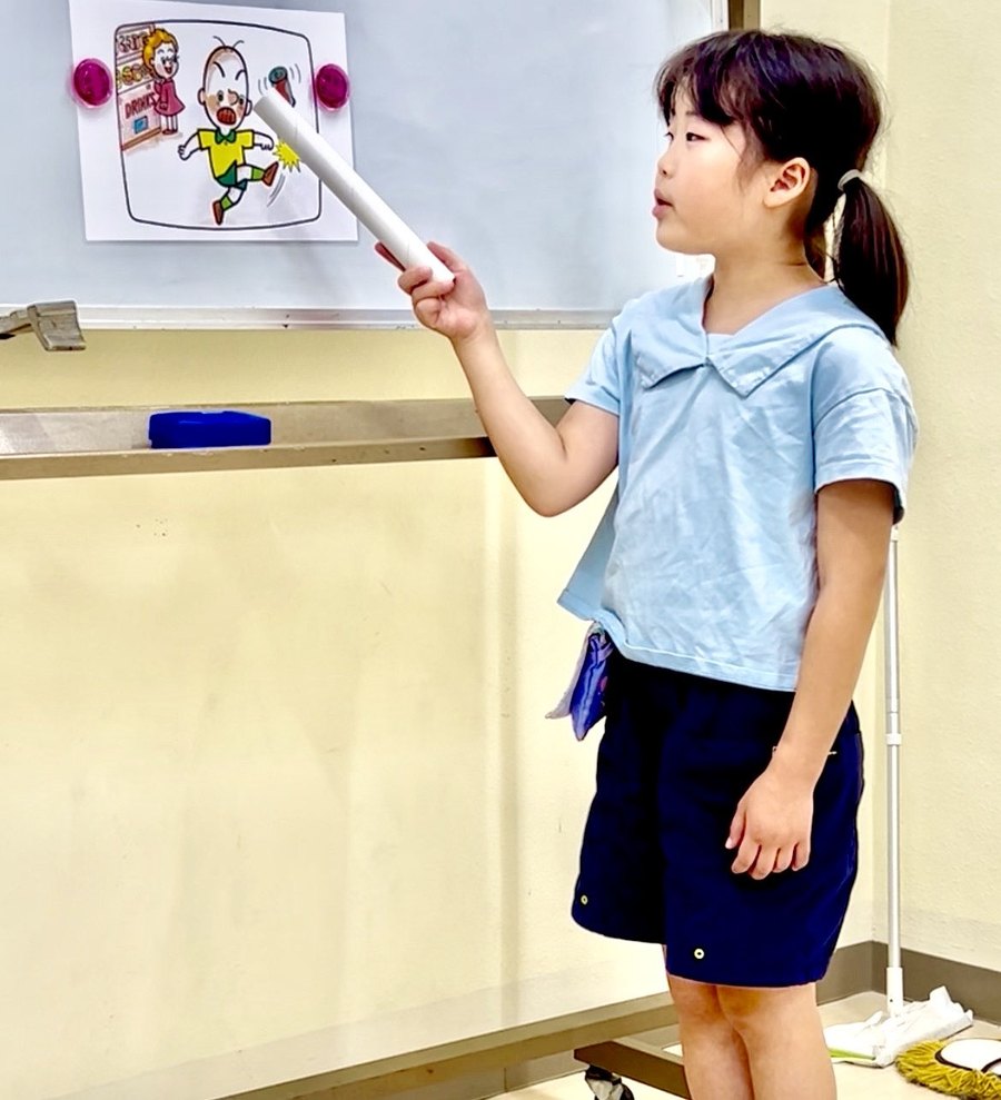 指し棒を使ってホワイトボードの英語を読む女の子